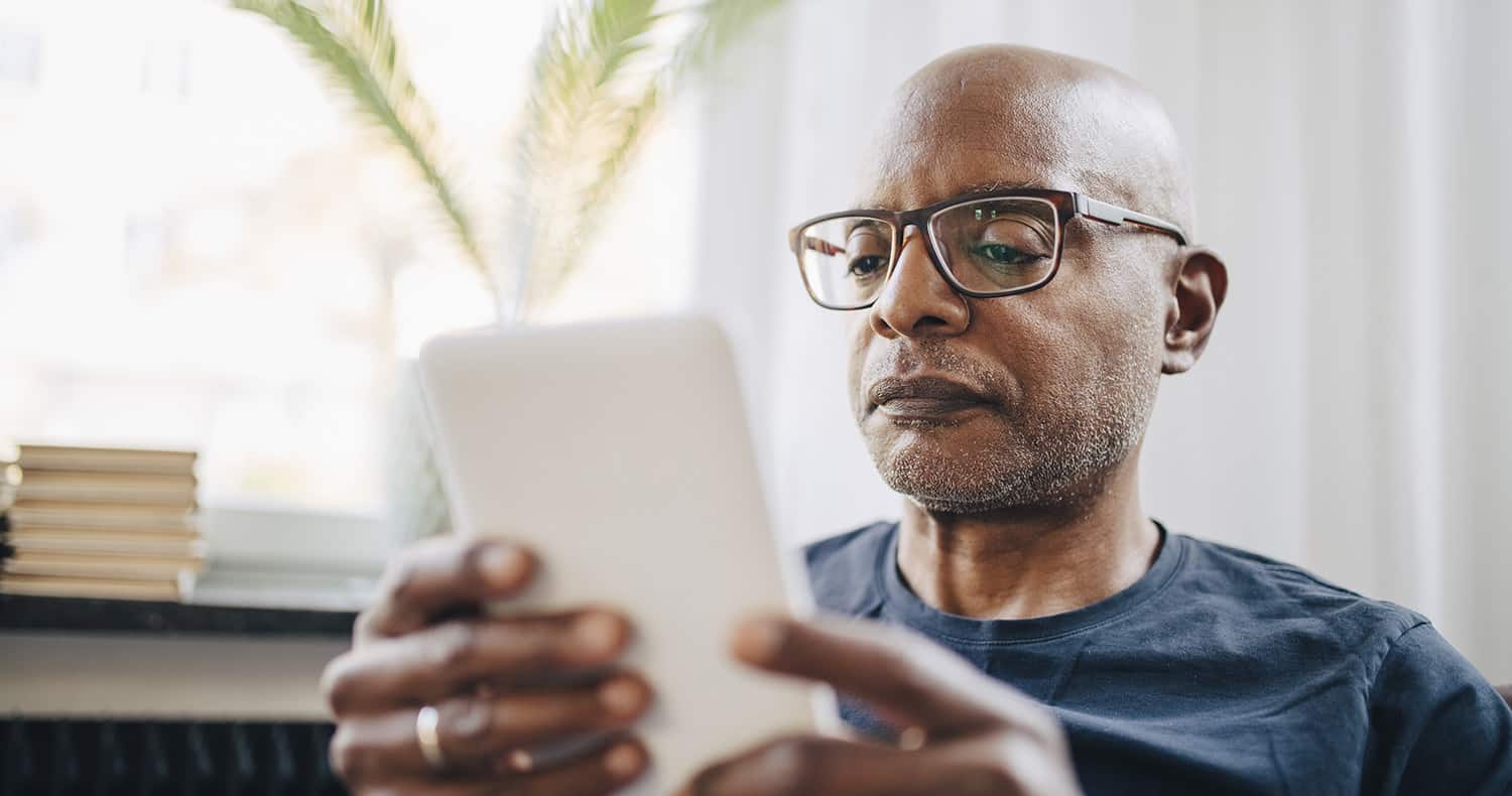 A retired man reading about life settlements on his tablet