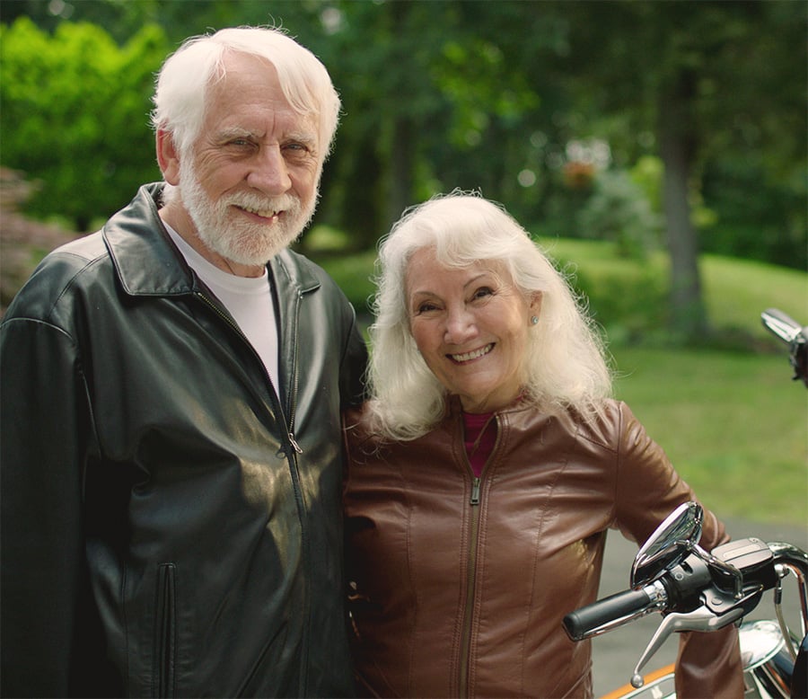 An active senior couple next to a motorcycle